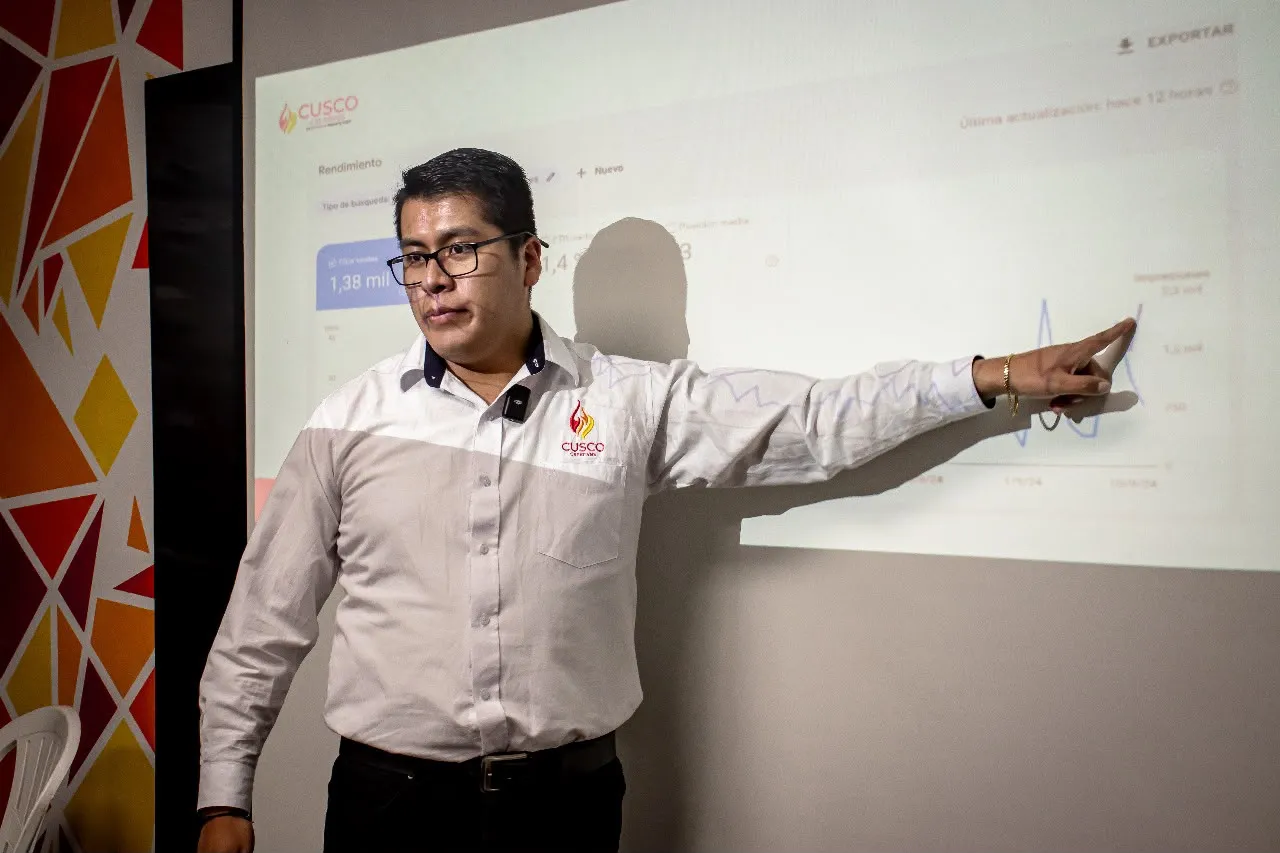 Paul Pumalloclla señala una gráfica de visitas desde Google durante el taller SEO para turismo en el auditorio de Cusco Creativos
